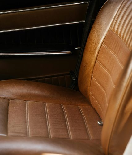 Close-up of a vintage car's interior featuring brown leather seats.
